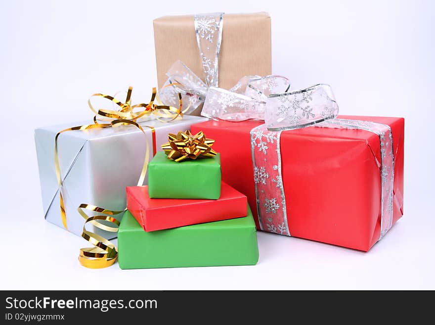 Gifts in silver, green, brown and red wrapping with bows on white background. Gifts in silver, green, brown and red wrapping with bows on white background