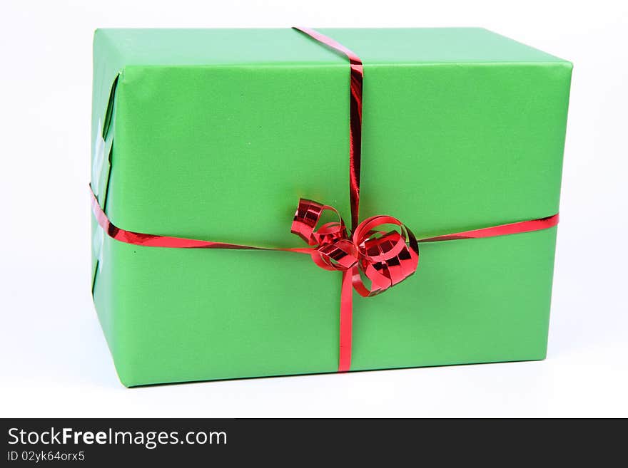 Gift in green wrapping with a red bow on white background