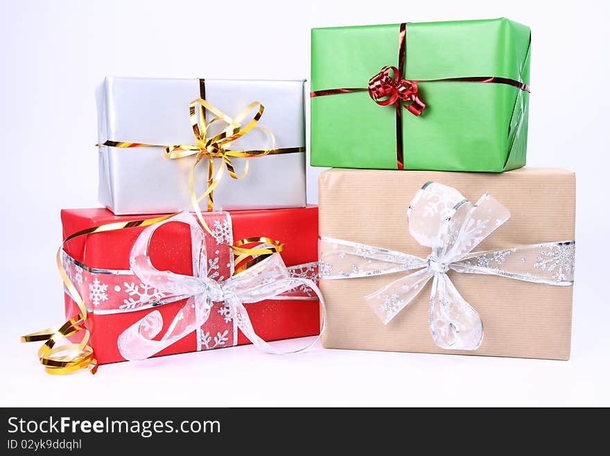 Gifts in silver, green, brown and red wrapping with bows on white background