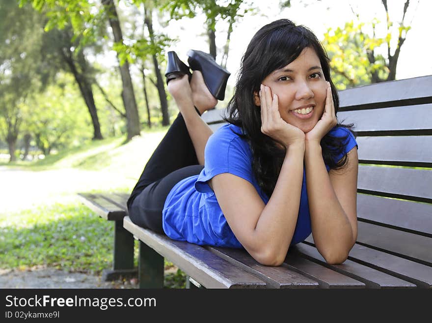 An Asian woman lying on a bench. An Asian woman lying on a bench