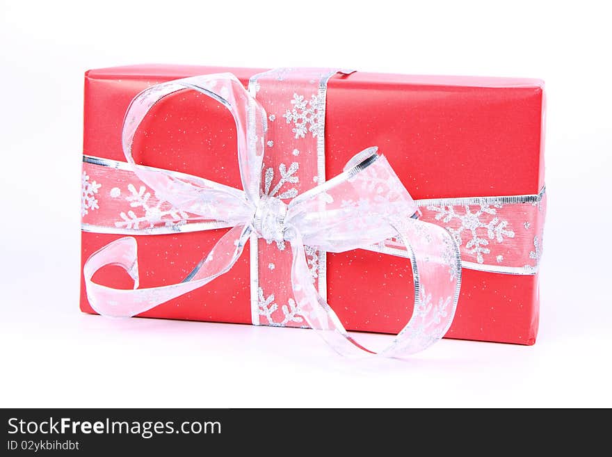 Gift in red wrapping with silver bow on white background