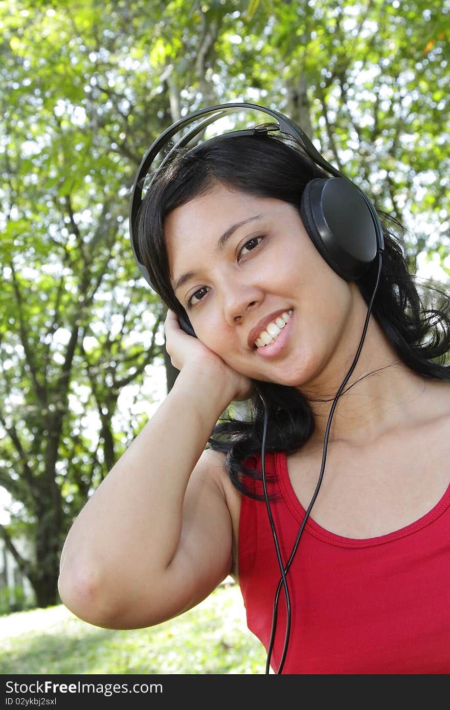 An Asian woman listening to music on headphones