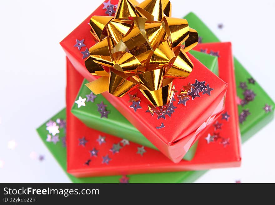 Pile of gifts in green and red wrapping with a golden bow decorated with star shaped confetti. Pile of gifts in green and red wrapping with a golden bow decorated with star shaped confetti