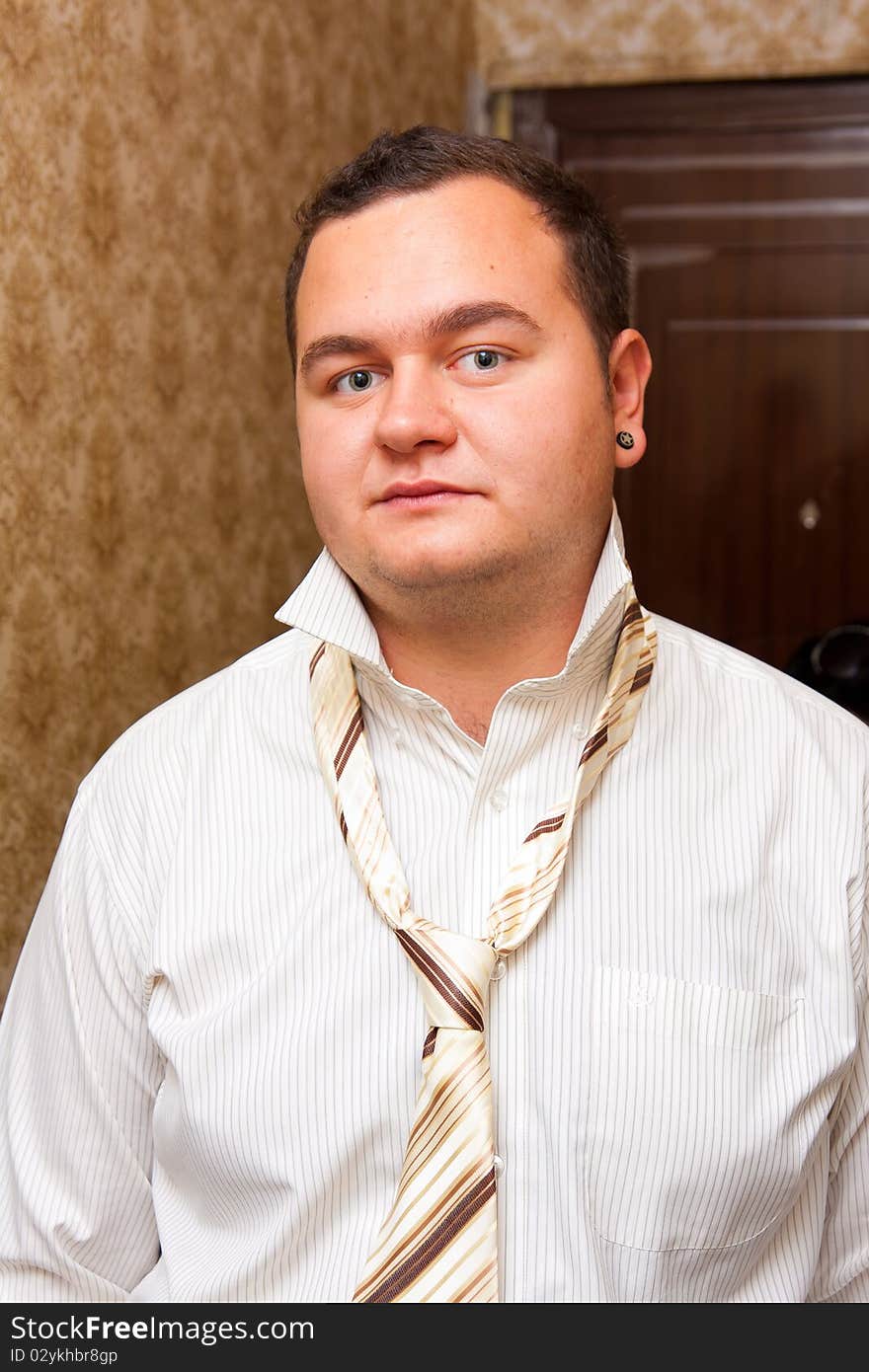 Indoors portrait of a young man wearing shirt with unfastened necktie