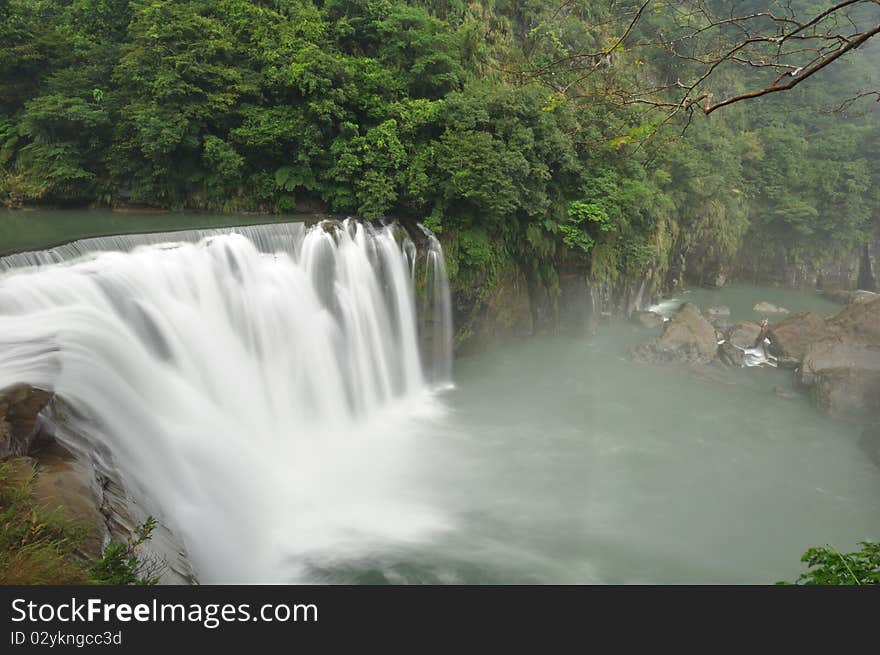 It is a waterfall in the cloudy day