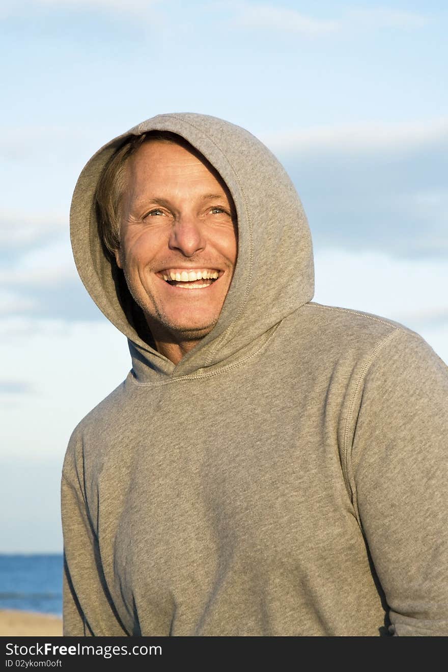 Happy laughing man in his forties wearing a grey hooded top.