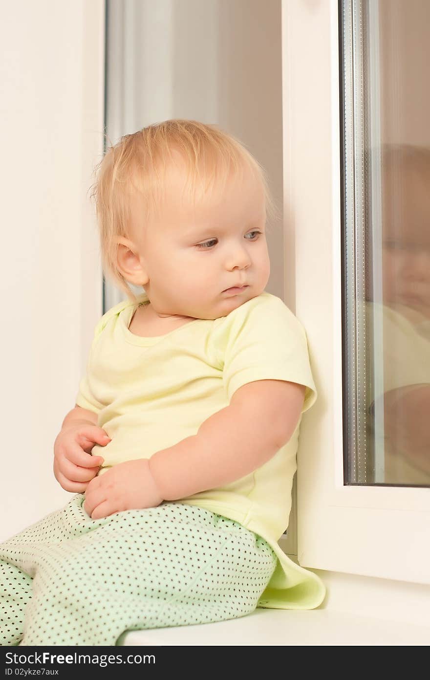 Adorable toddler girl sitting on the window sill look outside. Adorable toddler girl sitting on the window sill look outside