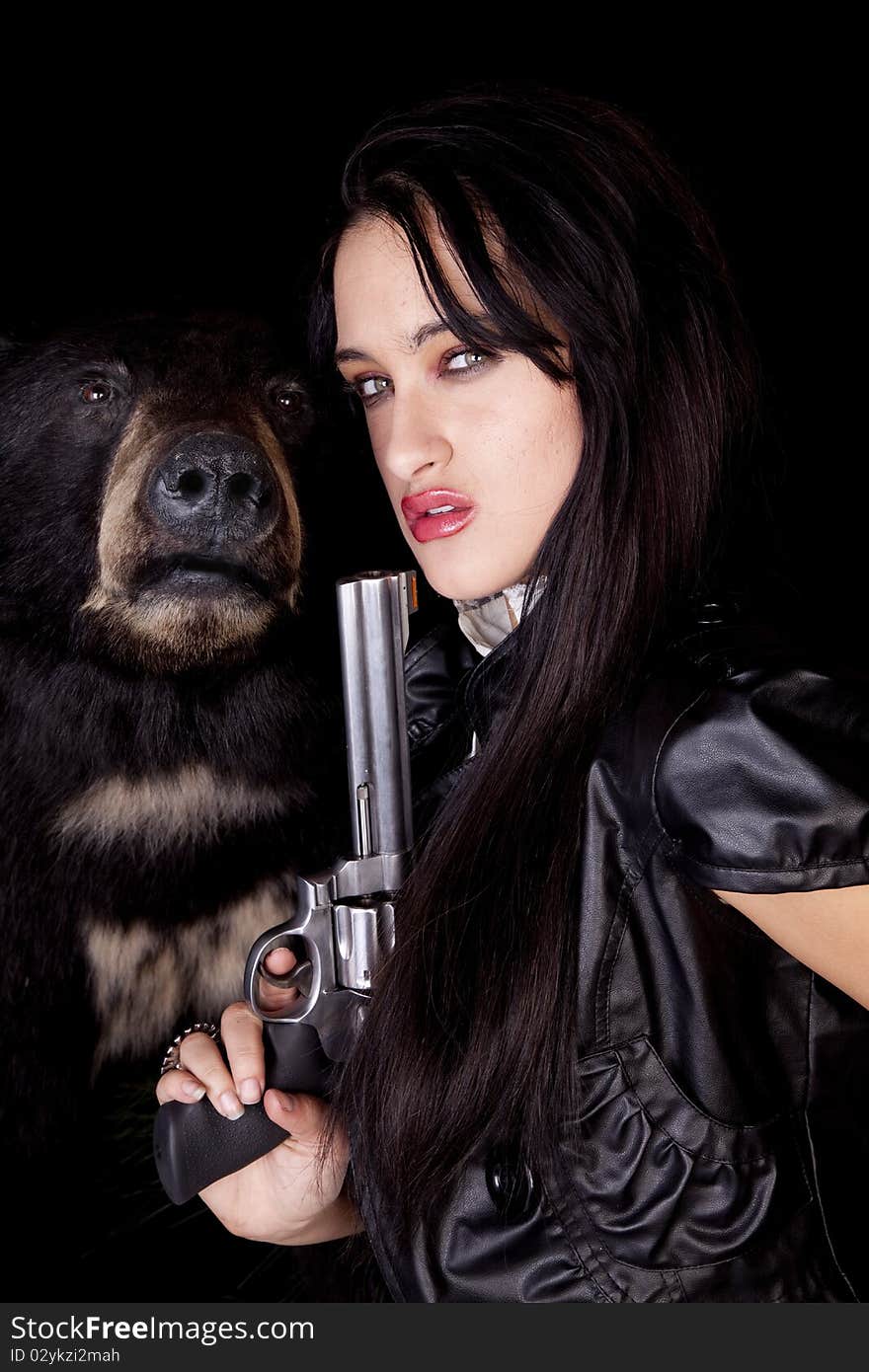 A woman is holding a gun by a black bear. A woman is holding a gun by a black bear.