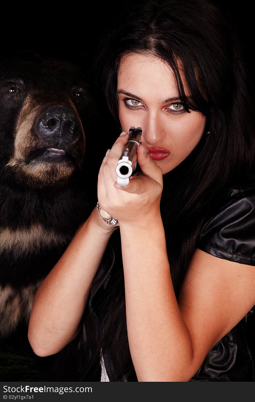 A woman is holding a gun by a black bear. A woman is holding a gun by a black bear.