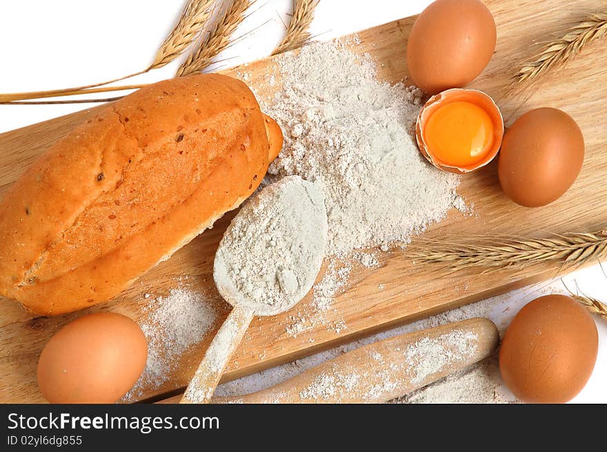 Still life of bread, eggs, cereas, flour and kitchen tools on a wooden board. Still life of bread, eggs, cereas, flour and kitchen tools on a wooden board