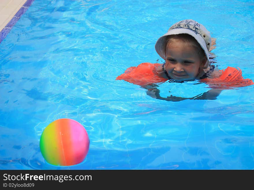 Girl swimming in armlets in a pool with a ball. Girl swimming in armlets in a pool with a ball