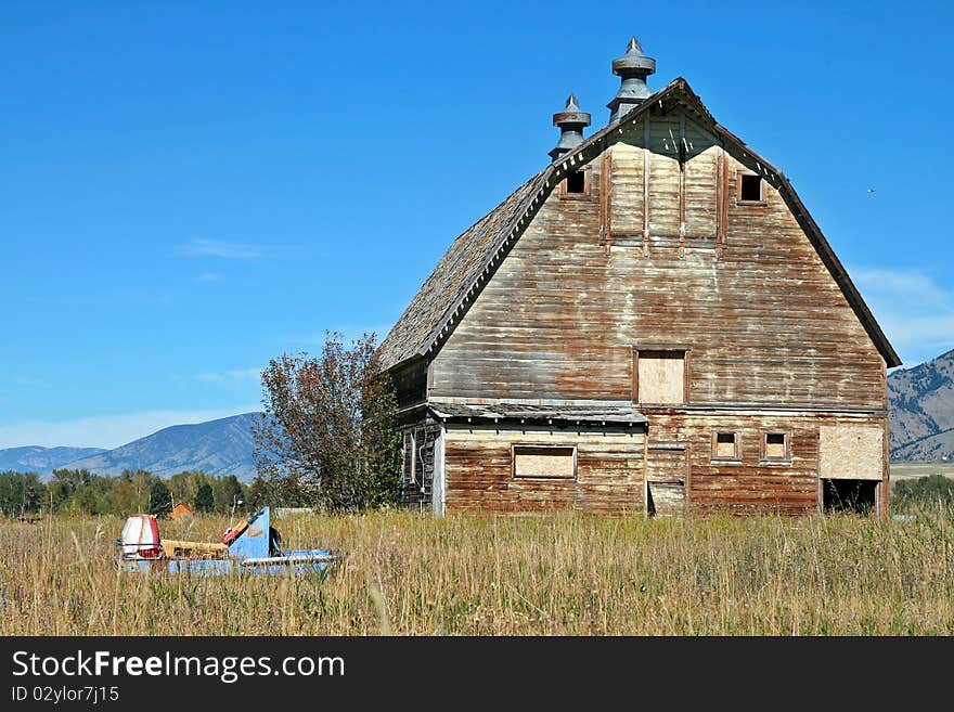 An old abandoned barn and broken down snowmobile in a field in Montana. An old abandoned barn and broken down snowmobile in a field in Montana.