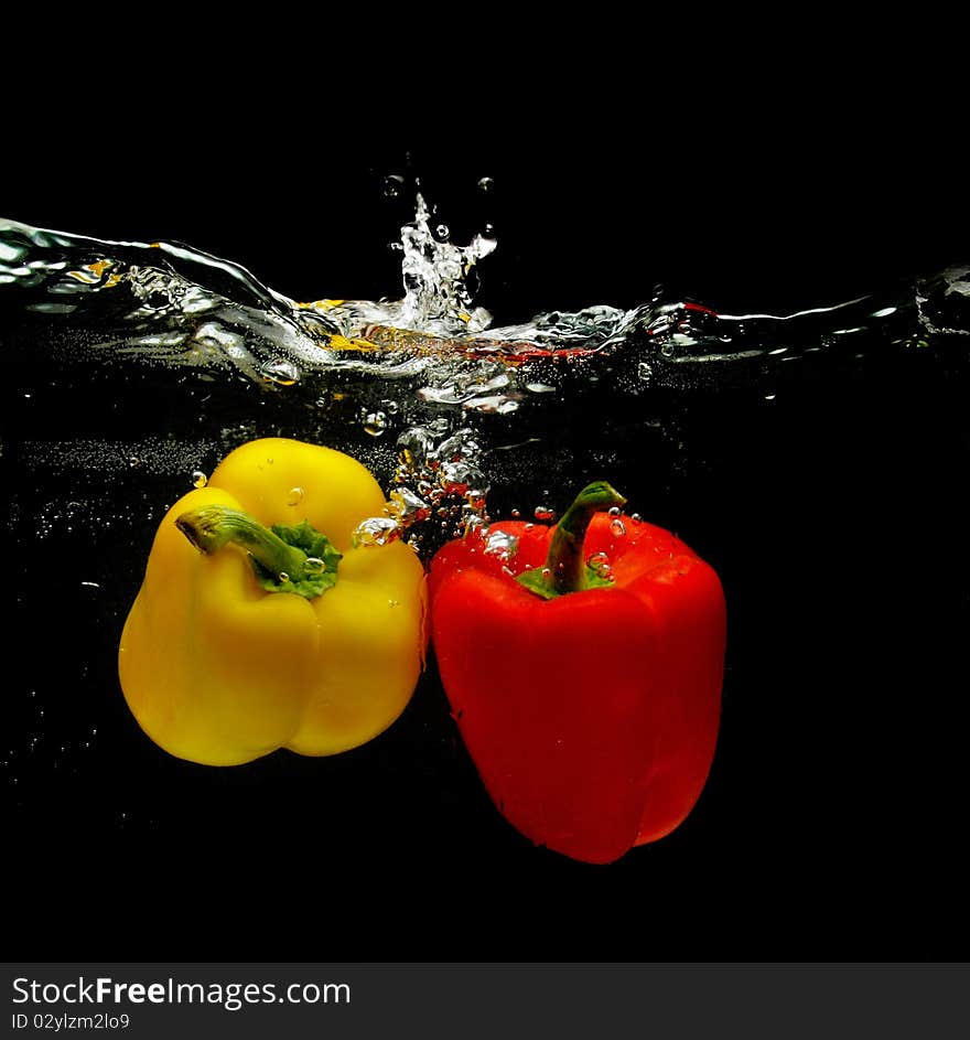 Red And Yellow Peppers Splashing Into Water