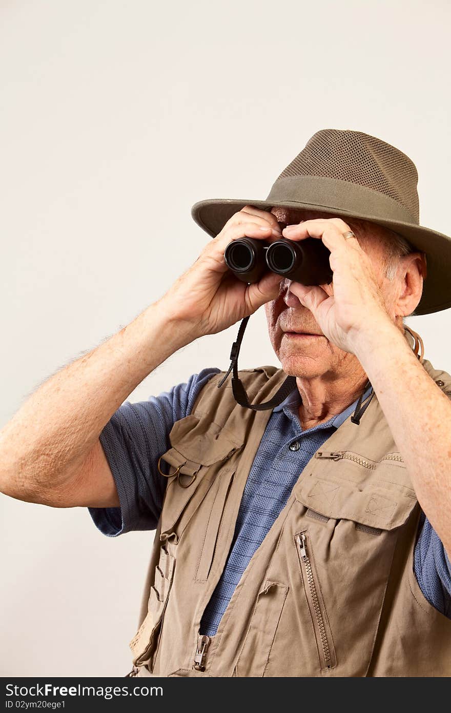 Mature man wearing hat and vest looking through binoculars. Mature man wearing hat and vest looking through binoculars.