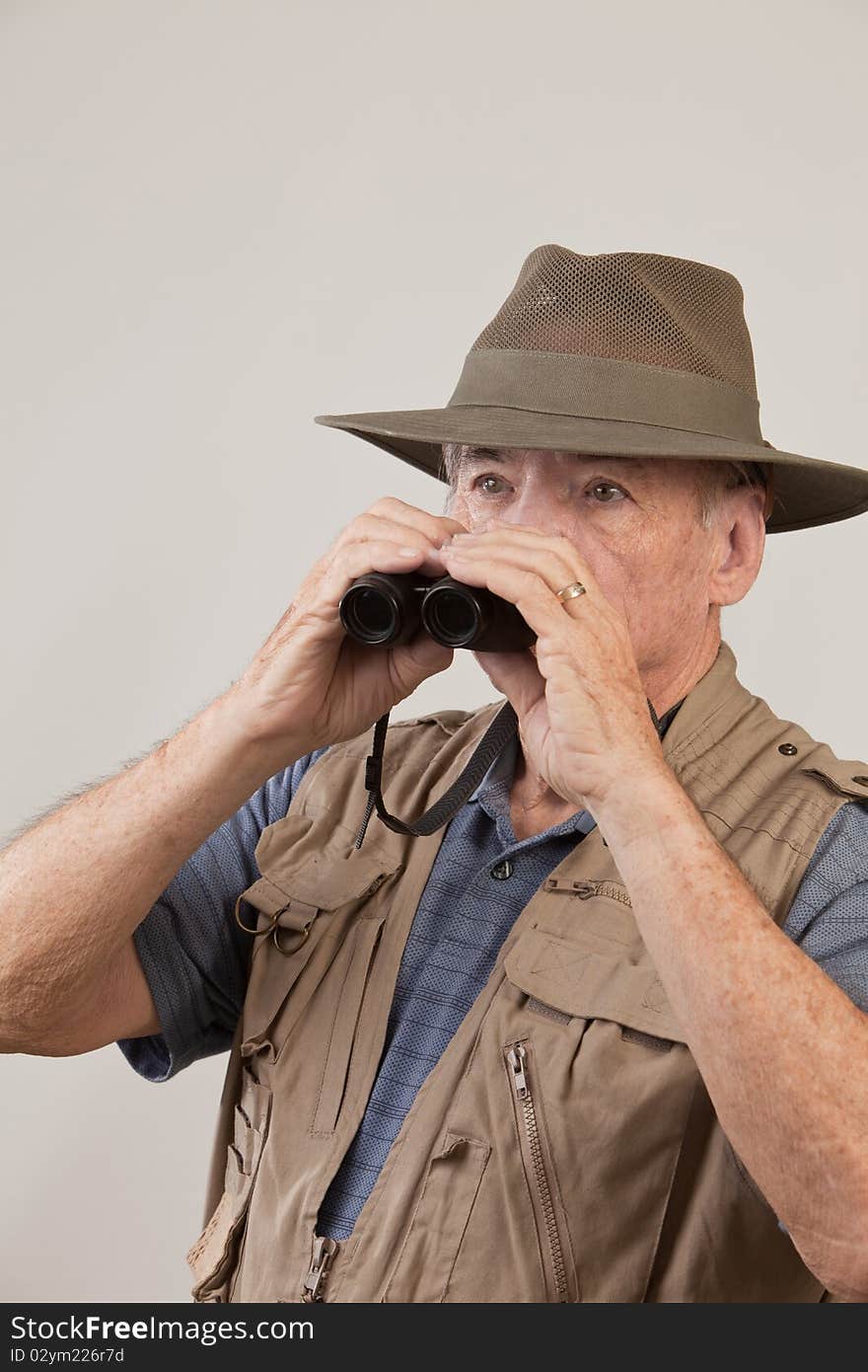 Mature man wearing hat and vest and holding binoculars. Mature man wearing hat and vest and holding binoculars.