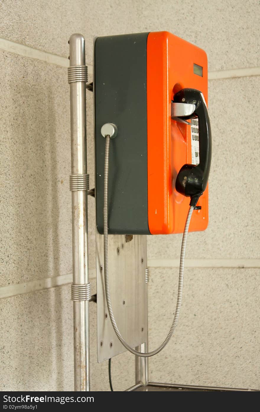 Public telephone boxes, orange Located very near the wall.