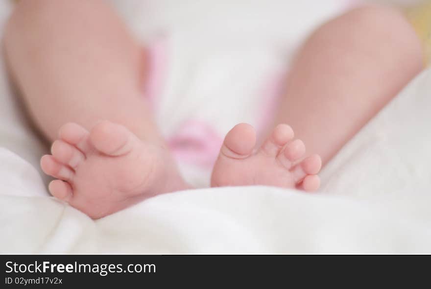 Legs of the baby on a white bedspread.