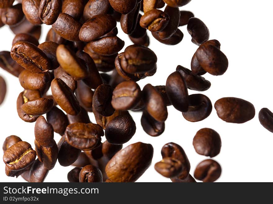 Falling grain roasted coffee on the side of a white background, photographed with a shallow depth of field. Falling grain roasted coffee on the side of a white background, photographed with a shallow depth of field