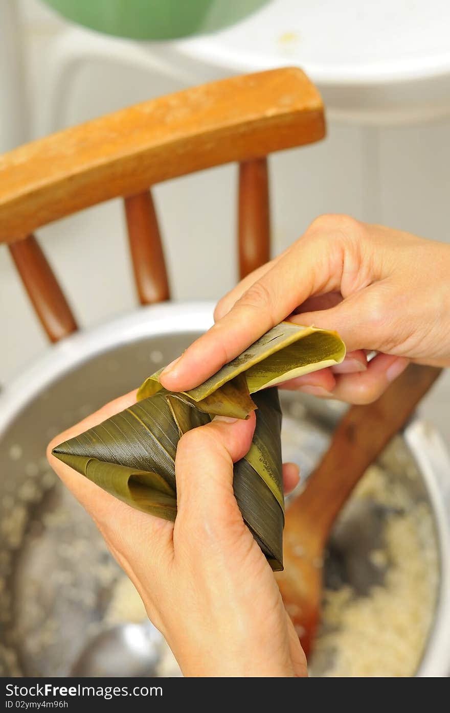 Final stage of wrapping a dumpling with bamboo leaves. Asian style traditional cuisine. Final stage of wrapping a dumpling with bamboo leaves. Asian style traditional cuisine.