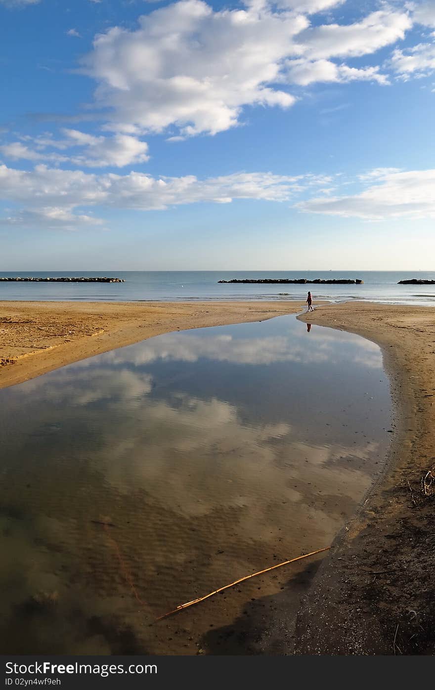 A man walks on deserted beach in early morning of a bright sunny day. A man walks on deserted beach in early morning of a bright sunny day