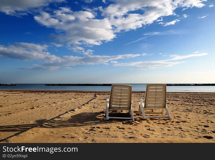 Two abandoned deckchairs in deserted beach. Two abandoned deckchairs in deserted beach