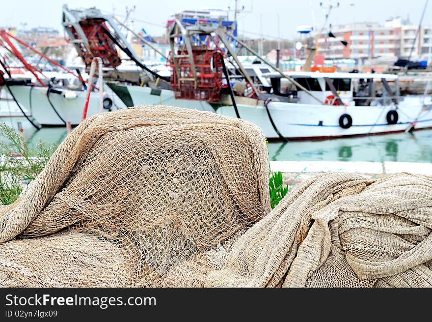 Fishing nets on a harbor's pier with fishing boats in background