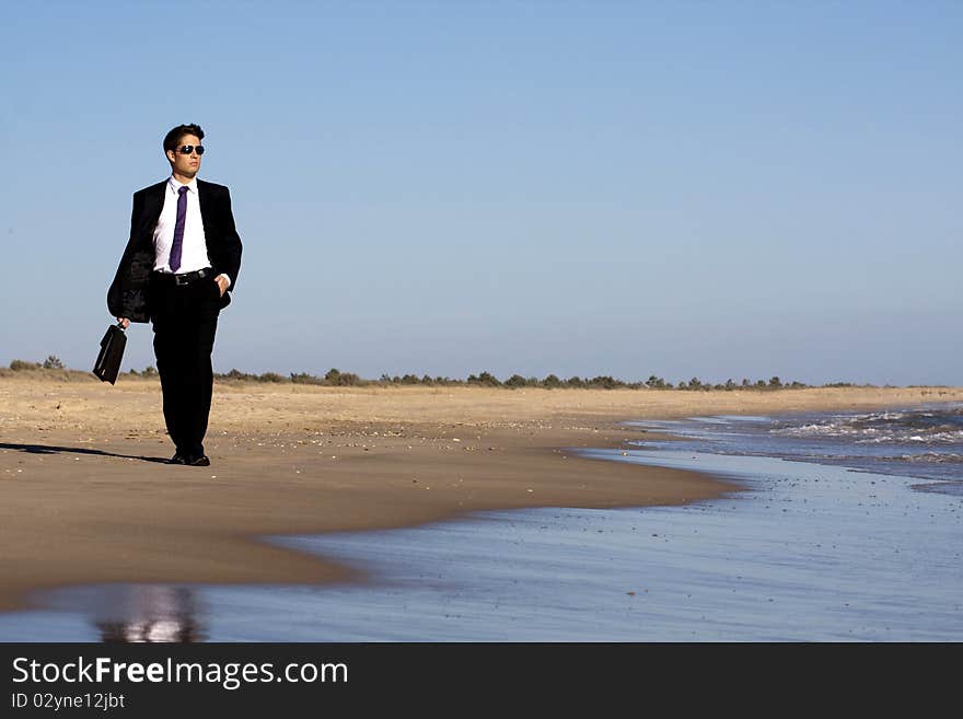 Close up view of a bunisess man in a dark suit walking on the beach. Close up view of a bunisess man in a dark suit walking on the beach.