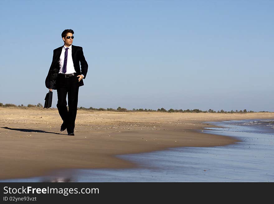 Close up view of a bunisess man in a dark suit walking on the beach. Close up view of a bunisess man in a dark suit walking on the beach.