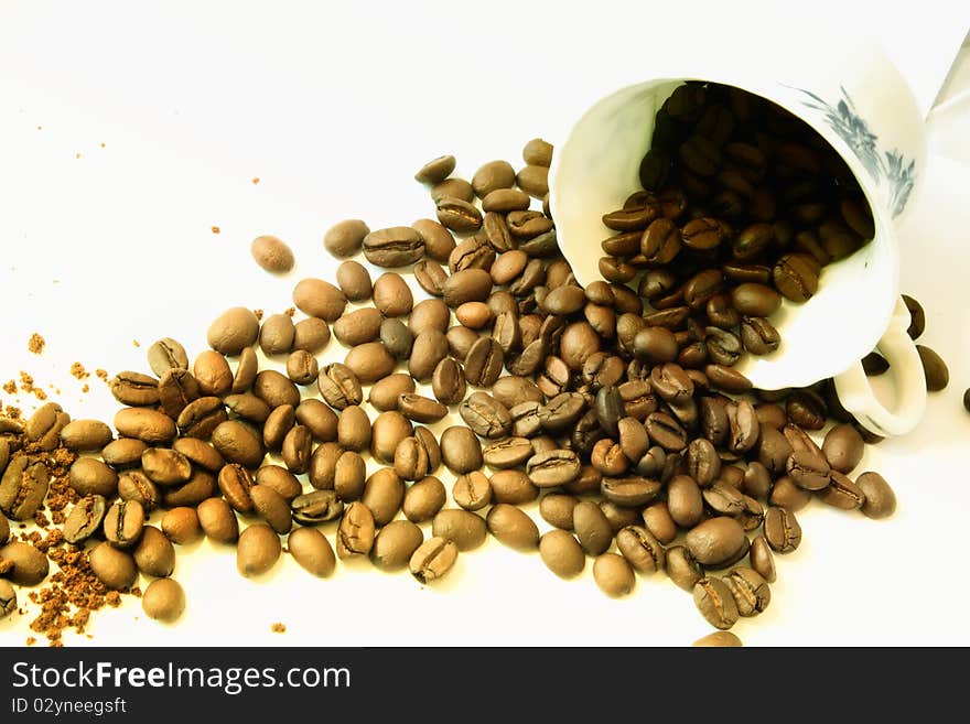 Coffee beans poured from a fine porcelain coffee cup. Coffee beans poured from a fine porcelain coffee cup