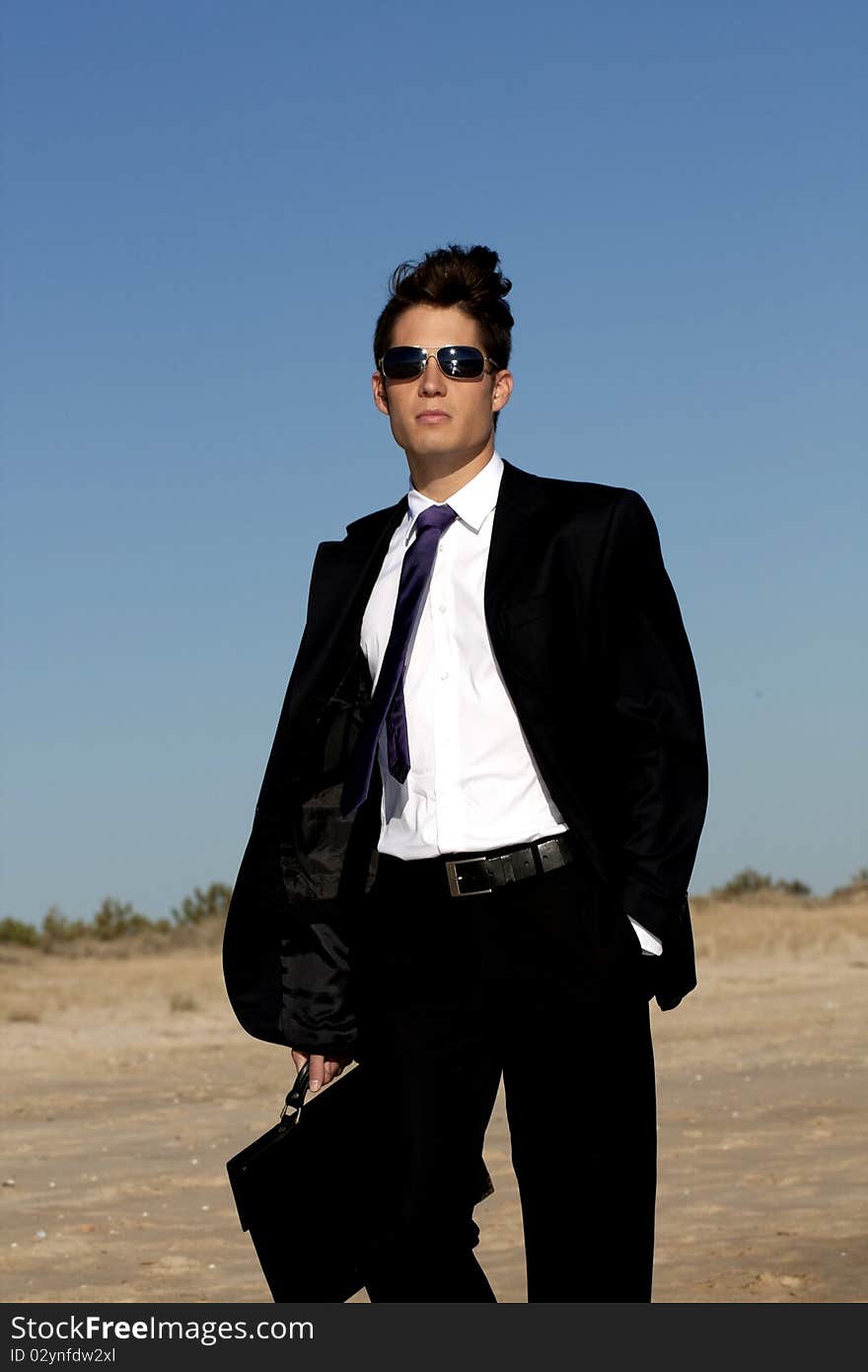 Close up view of a bunisess man in a dark suit walking on the beach. Close up view of a bunisess man in a dark suit walking on the beach.