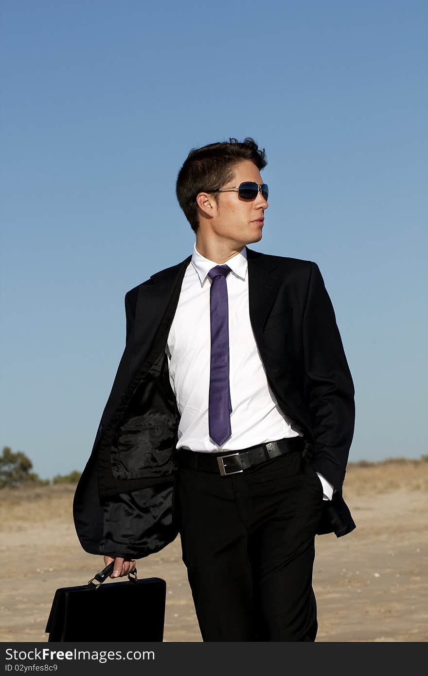 Close up view of a bunisess man in a dark suit walking on the beach. Close up view of a bunisess man in a dark suit walking on the beach.