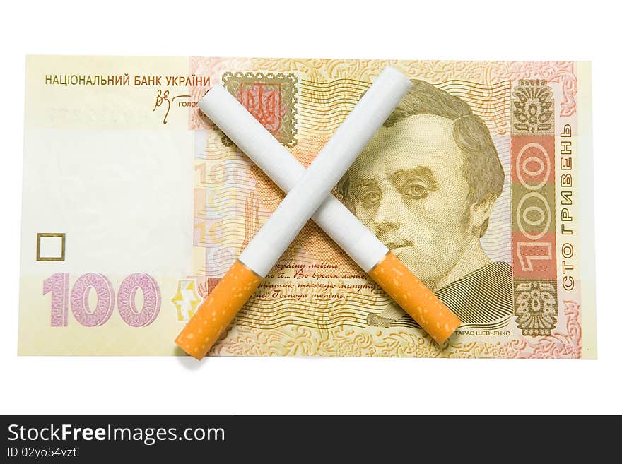 Two cigarettes crossed over one hundred hrivna bil - ukrainian currency. Isolated on white