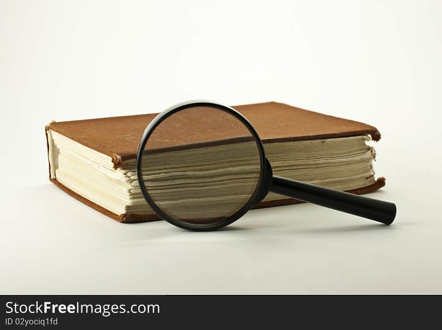 Old book with Magnifying Glass on a white background