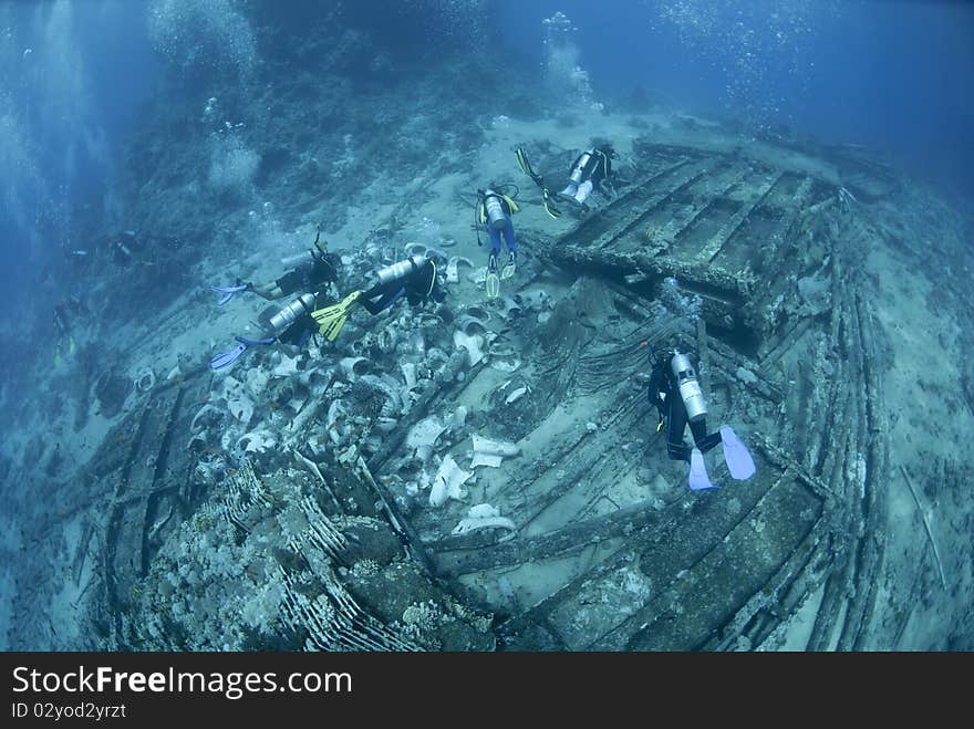 Group of scuba divers exploring the wrecked remains of a ship and its cargo. Yolanda reef, Ras Mohamed National Park, Red Sea, Egypt. Group of scuba divers exploring the wrecked remains of a ship and its cargo. Yolanda reef, Ras Mohamed National Park, Red Sea, Egypt.