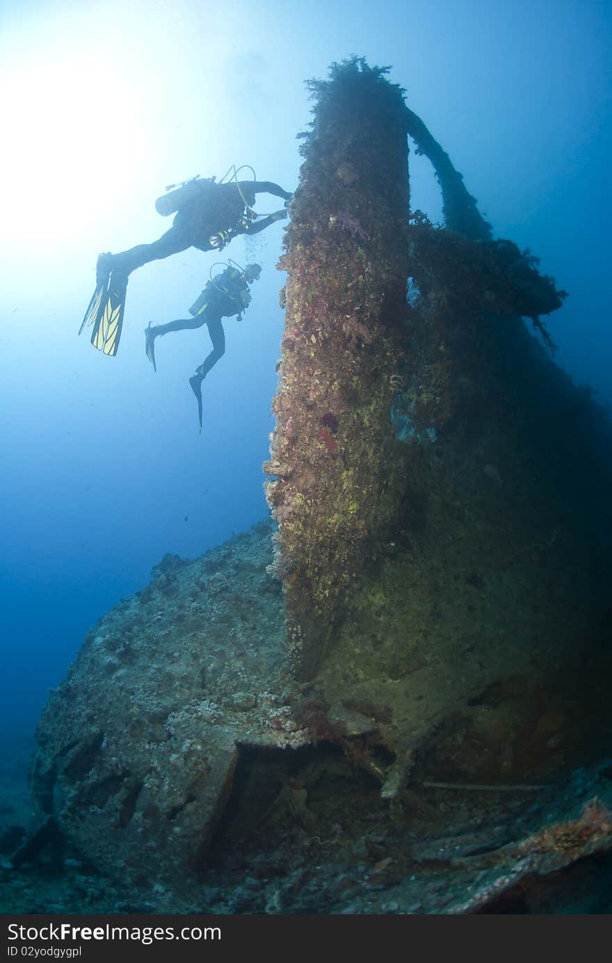 Scuba divers exploring the propellor area of a shipwreck. Dunraven, Beacon rock, Red Sea, Egypt. Scuba divers exploring the propellor area of a shipwreck. Dunraven, Beacon rock, Red Sea, Egypt.