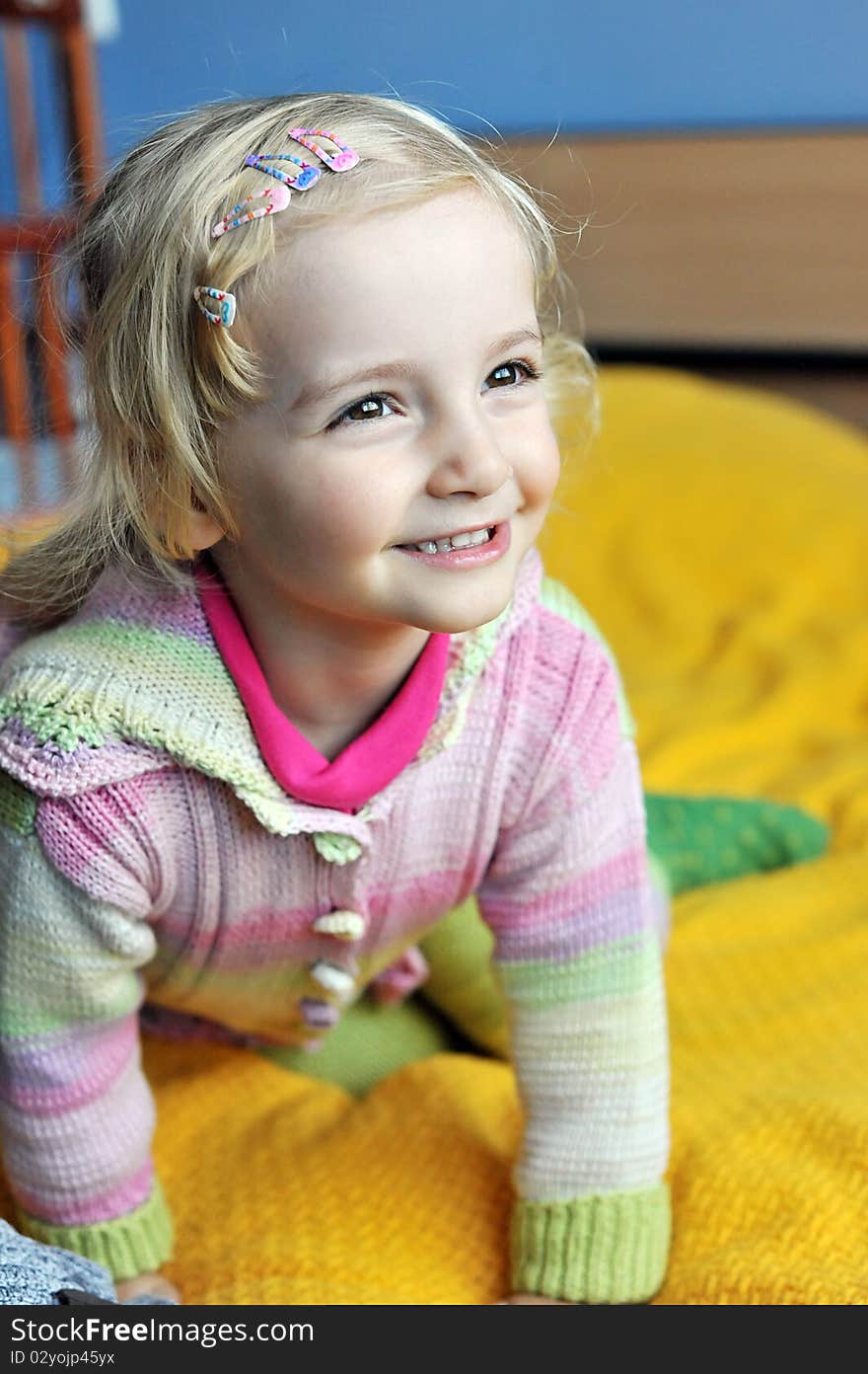 Cheerful little girl sits on bed of parents