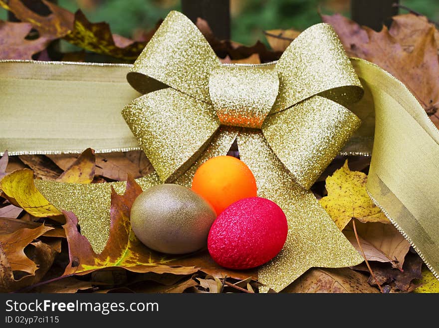 Gold, Red, and Orange Nest Eggs against a gold ribbon in autumn leaves suggest the diversified portfolio needed for retirement in the autumn of a couple's life together. Gold, Red, and Orange Nest Eggs against a gold ribbon in autumn leaves suggest the diversified portfolio needed for retirement in the autumn of a couple's life together.