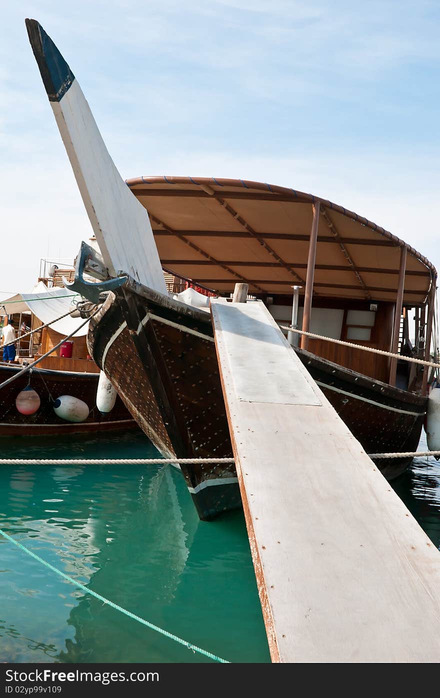 A modern dhow anchored in the bay in Doha, Qatar. The gangway leads the way onto the boat. A modern dhow anchored in the bay in Doha, Qatar. The gangway leads the way onto the boat.