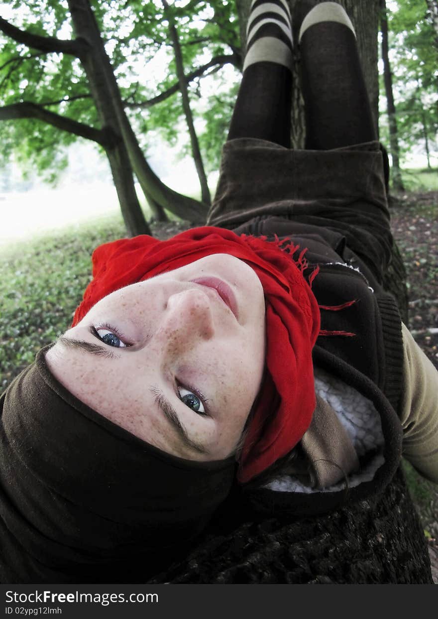 Beautiful girl with red scarf, lying on the branch