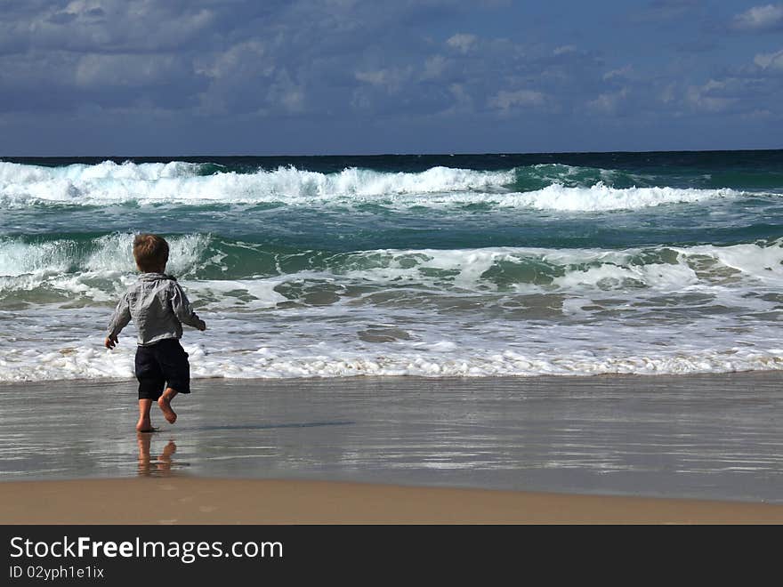 3-year-old boy looks at the sea. Autumn sea, strong waves, sharp colors.