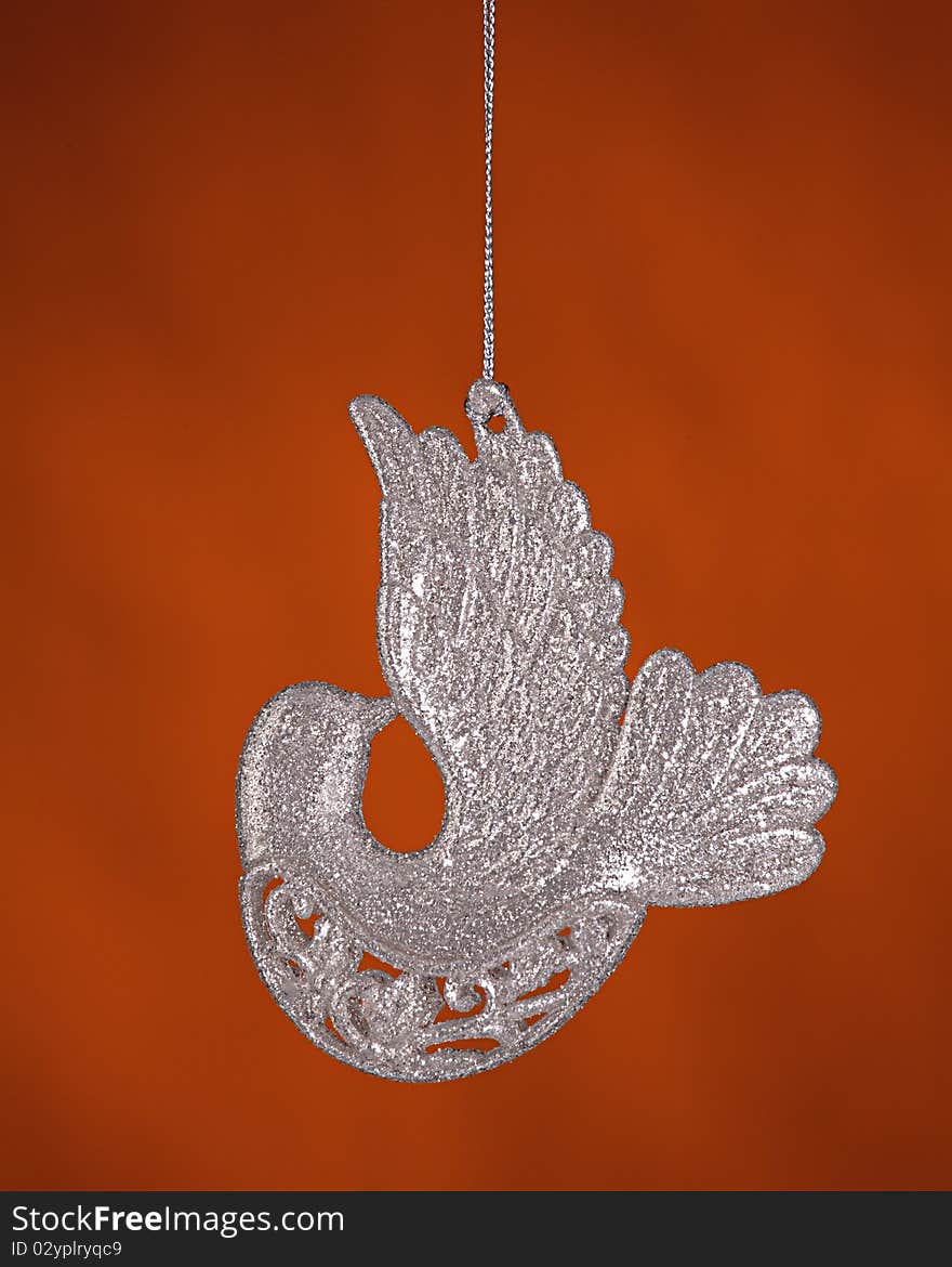 A silver sparkle color dove bird Christmas tree ornament isolated against a gold background. A silver sparkle color dove bird Christmas tree ornament isolated against a gold background.