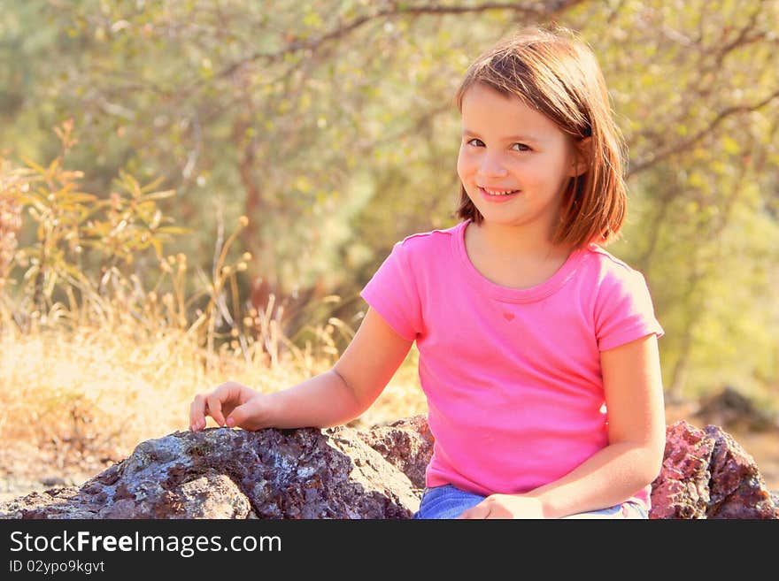 Young girl sitting on ricks with oak trees in the background. Young girl sitting on ricks with oak trees in the background.
