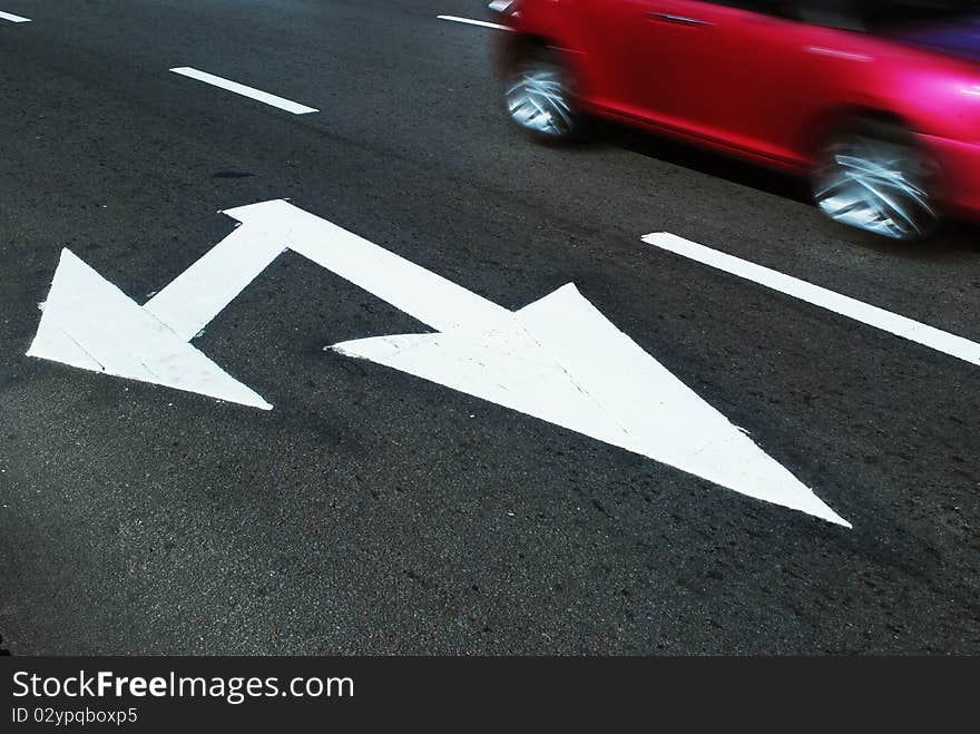 White arrow sign painted on pavement with blur red car. White arrow sign painted on pavement with blur red car