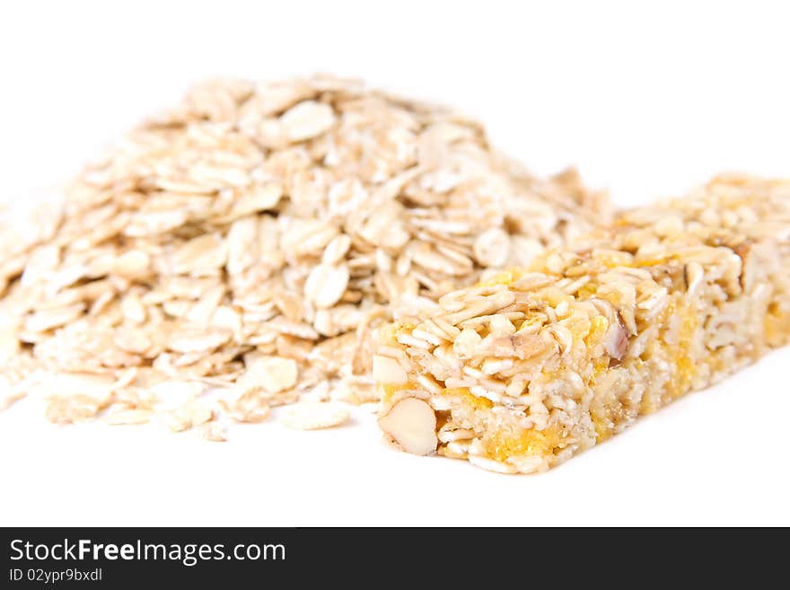 Muesli snack stick and oat flakes isolated on white