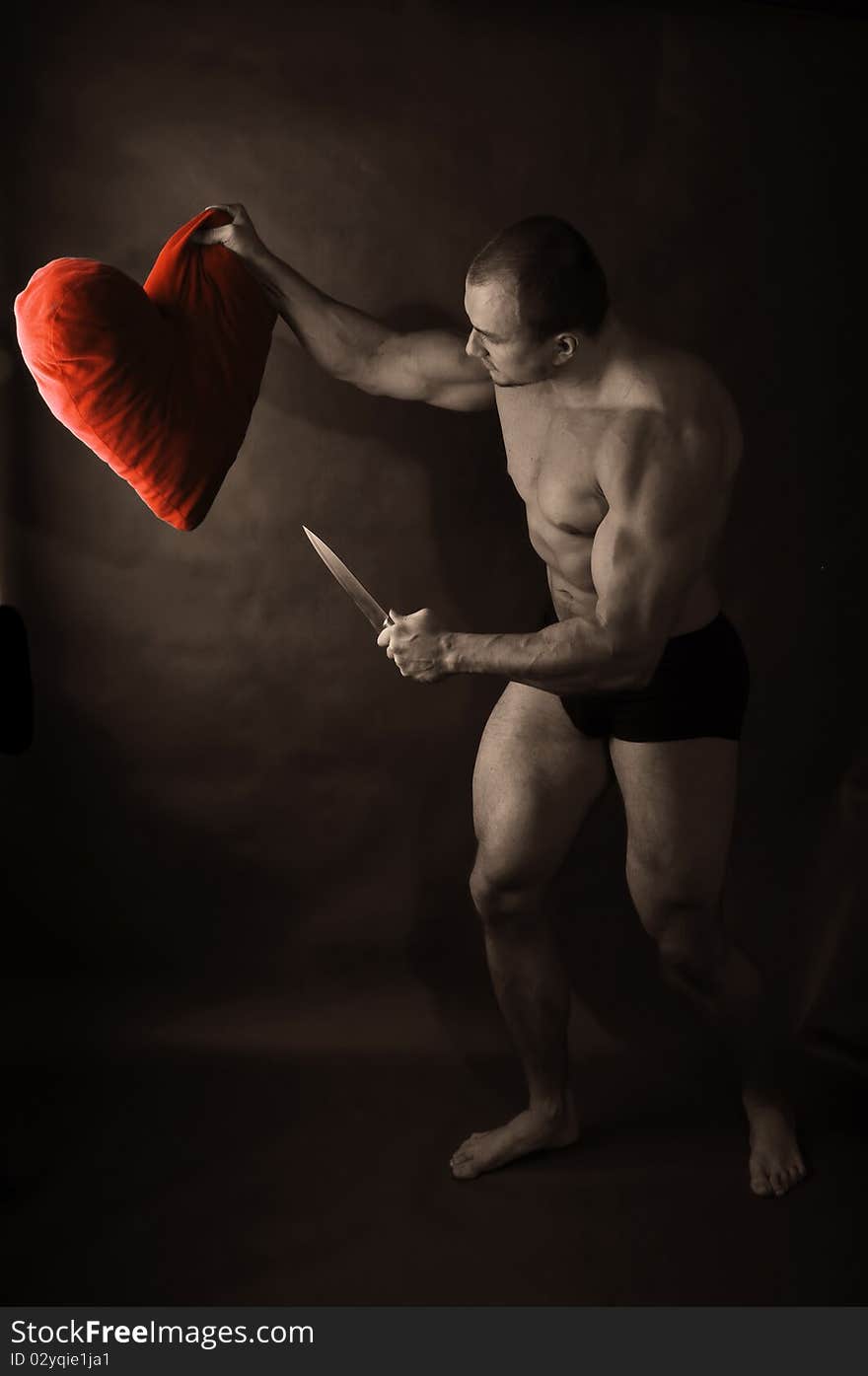 Muscular man with knife attacking red heart