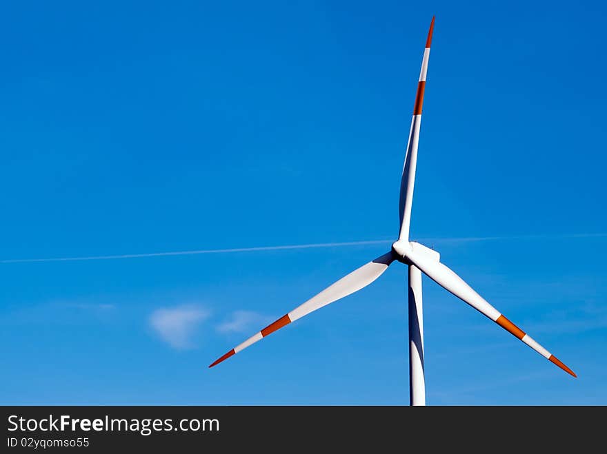 Large wind turbine turns against a blue sky