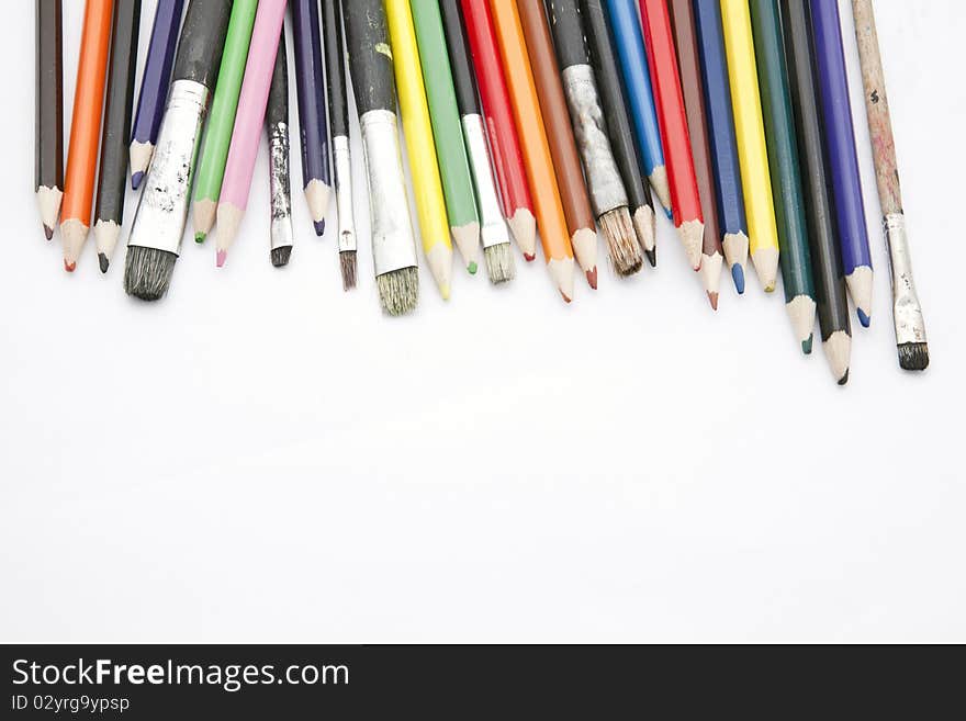 Paint brushes and color pencils isolated on white