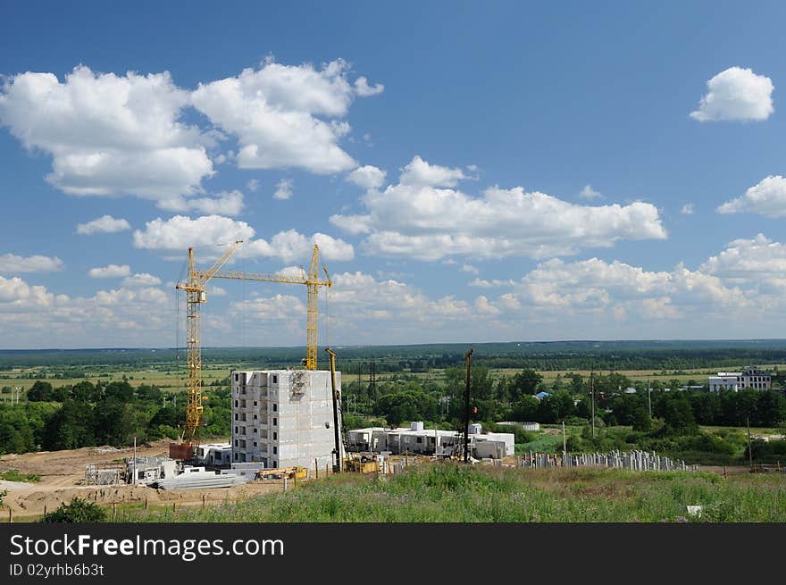 Panoramic view of the apartment building under construction against endless green fields. Panoramic view of the apartment building under construction against endless green fields