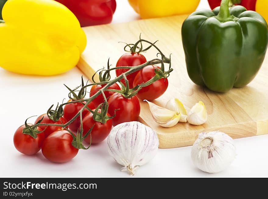 Vine, cherry tomatoes with colourful peppers lying on the cutting board. Vine, cherry tomatoes with colourful peppers lying on the cutting board