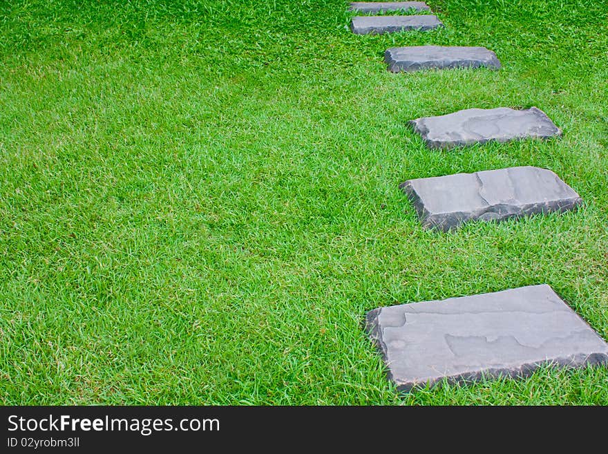 Stone alley as walk way on green grass. Stone alley as walk way on green grass.